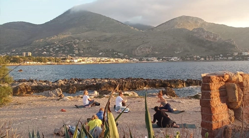 Women meditating/yoga in a green park near the sea