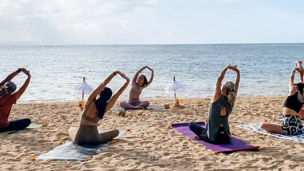 donne che praticano pilates con istruttrice sulla spiaggia