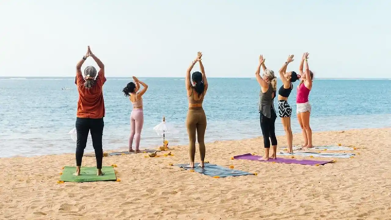 donne che praticano pilates con istruttrice sulla spiaggia