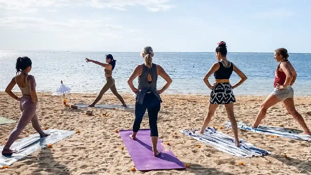 donne che praticano pilates con istruttrice sulla spiaggia