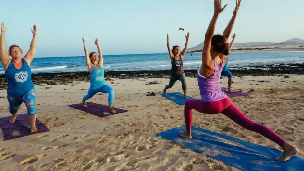 donne che praticano pilates con istruttrice sulla spiaggia